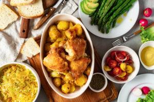 Abendessen mit der Außenküche zubereitet, verschiedenen Lebensmittel, gebackene Kartoffeln mit Hähnchenschenkel, Gemüse und Salate, Draufsicht, schmackhafte und gesunde Lebensmittel.