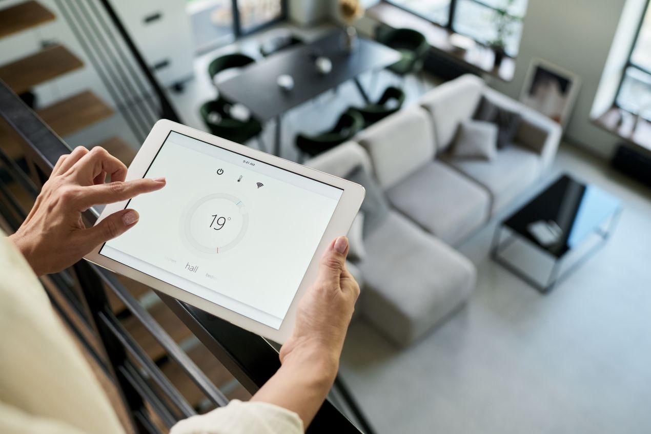Frau nutzt Tablet zur Heizungssteuerung beim Wohnzimmer gestalten mit Smart-Home-Technik