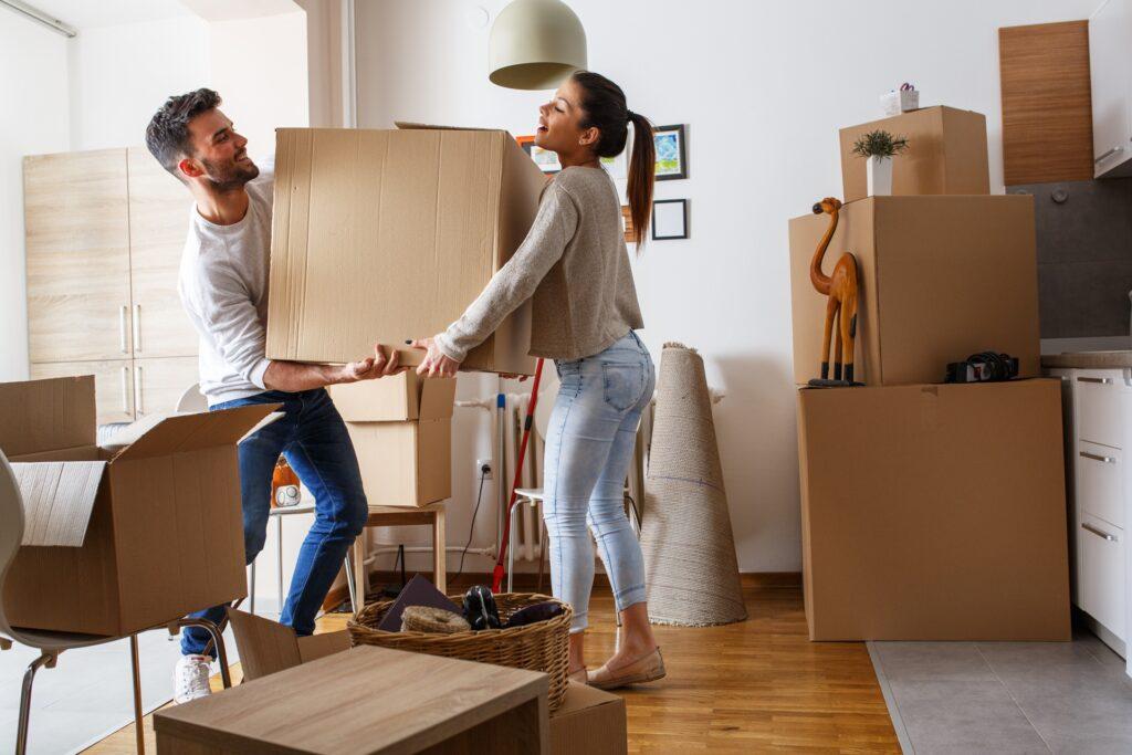 Paar hebt großen Umzugskarton im Wohnzimmer | Schrenzpapier