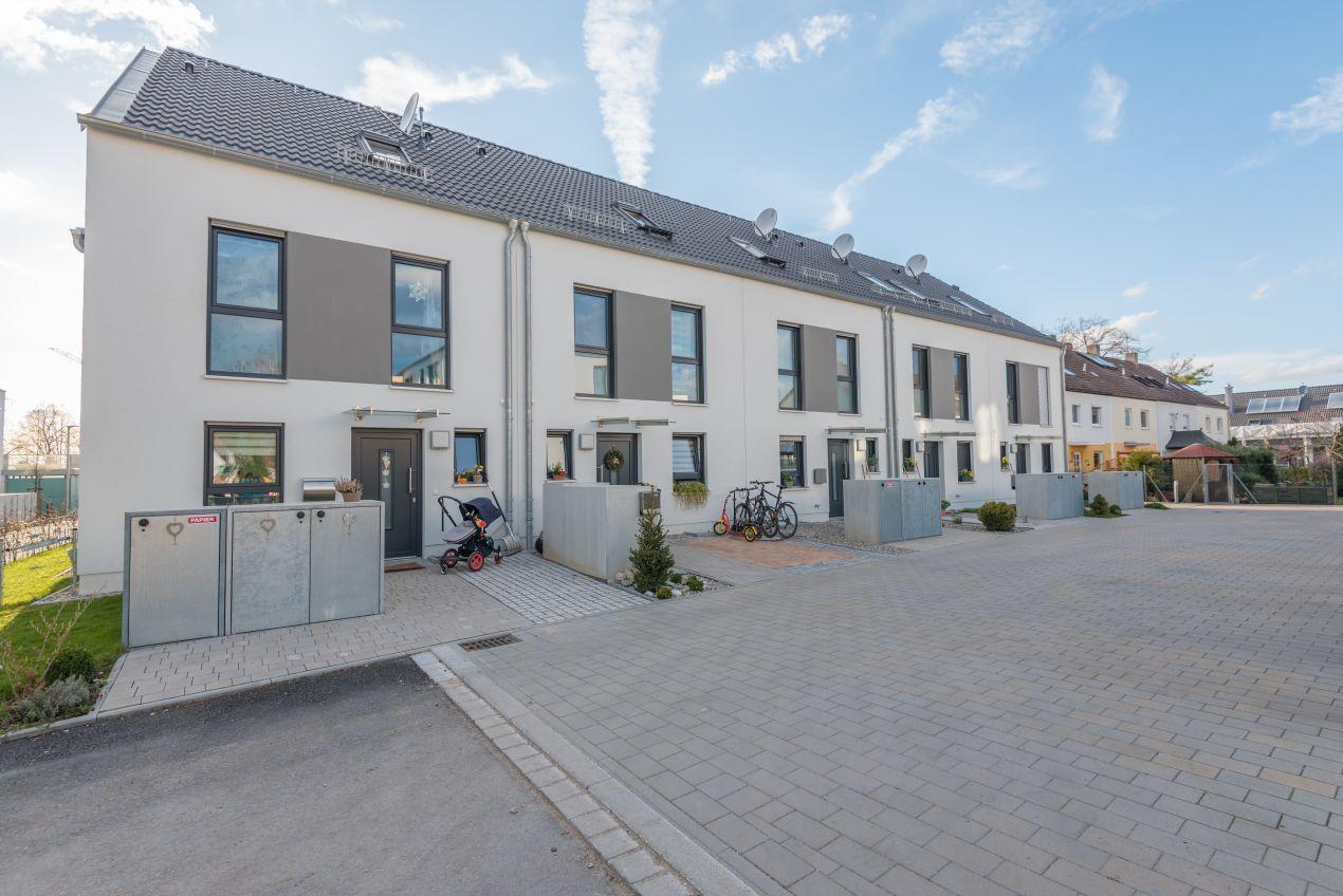 Mülleinhausung aus Metall vor einem modernen Reihenhaus, integriert in den Vorgarten mit klarer Linienführung und funktionalem Design