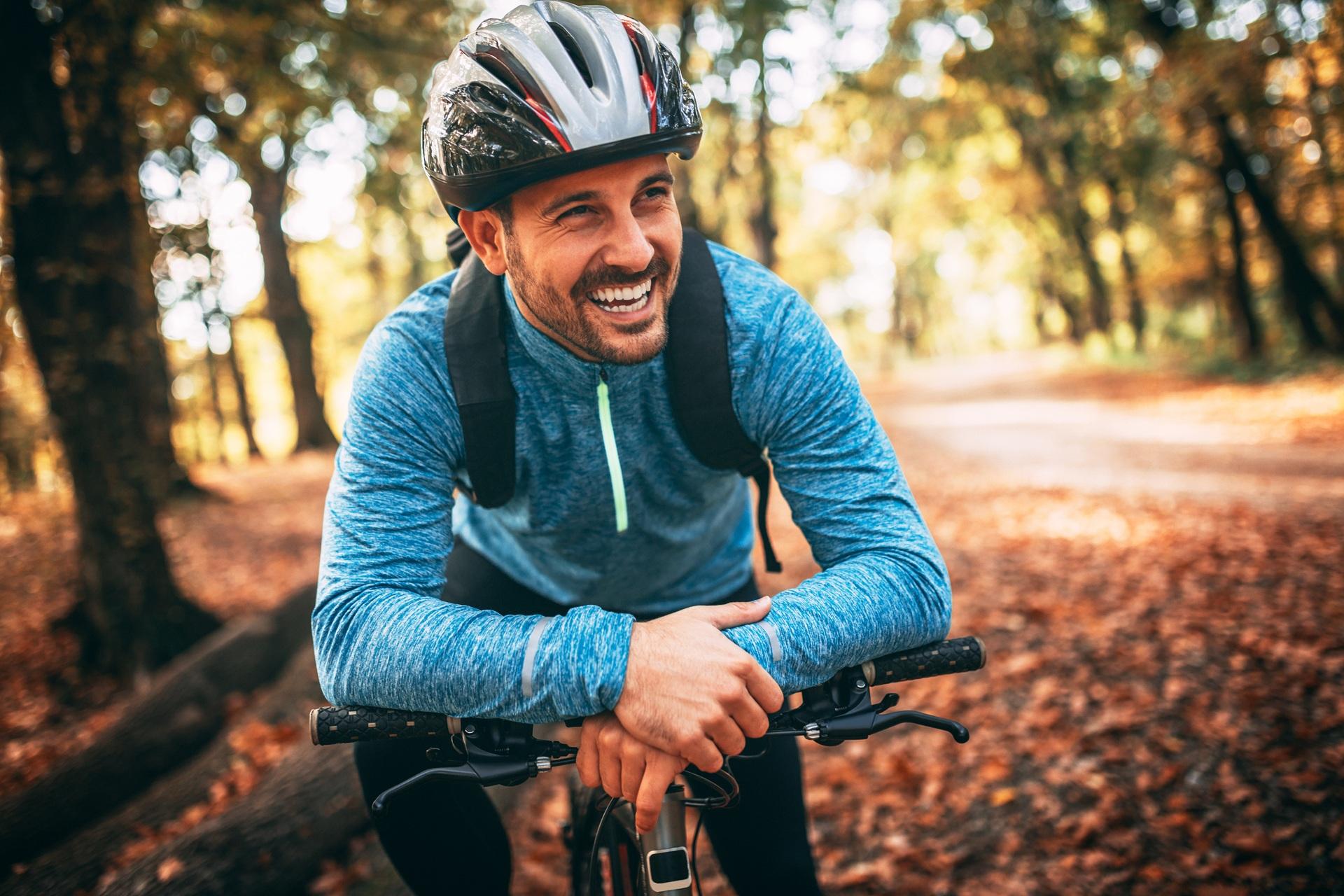 Zufriedener Radfahrer macht Pause im herbstlichen Wald | Inline Skates kaufen