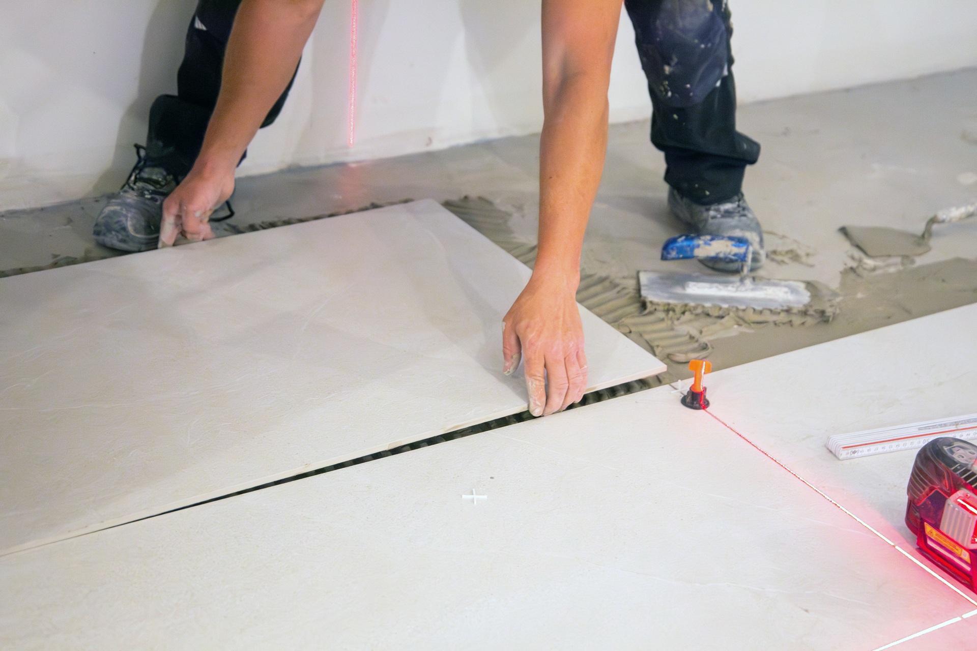 Handwerker richtet große Bodenfliese mit Laser aus | Klickfliese